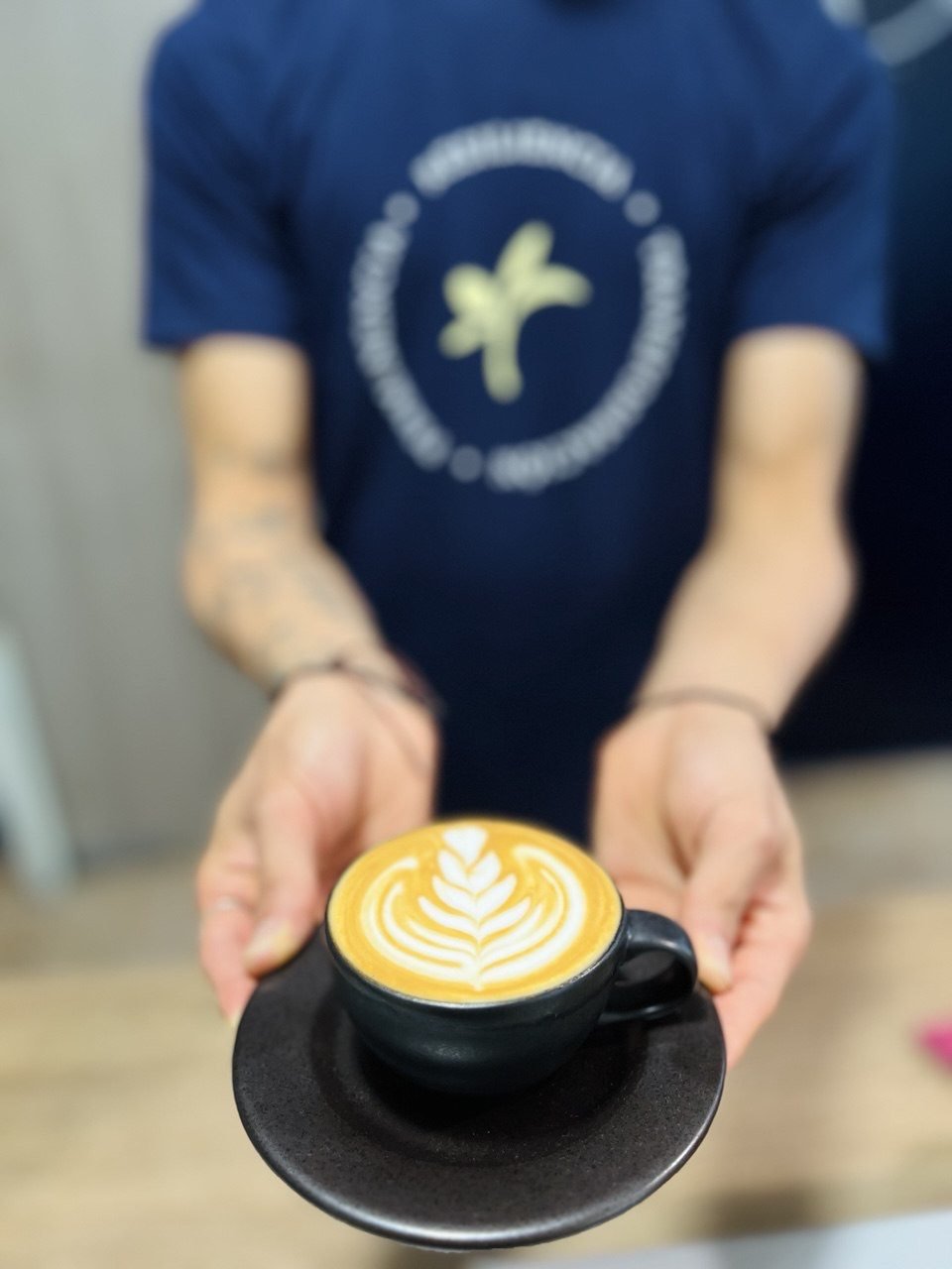 Barista de Esencia Café sirviendo un latte con arte