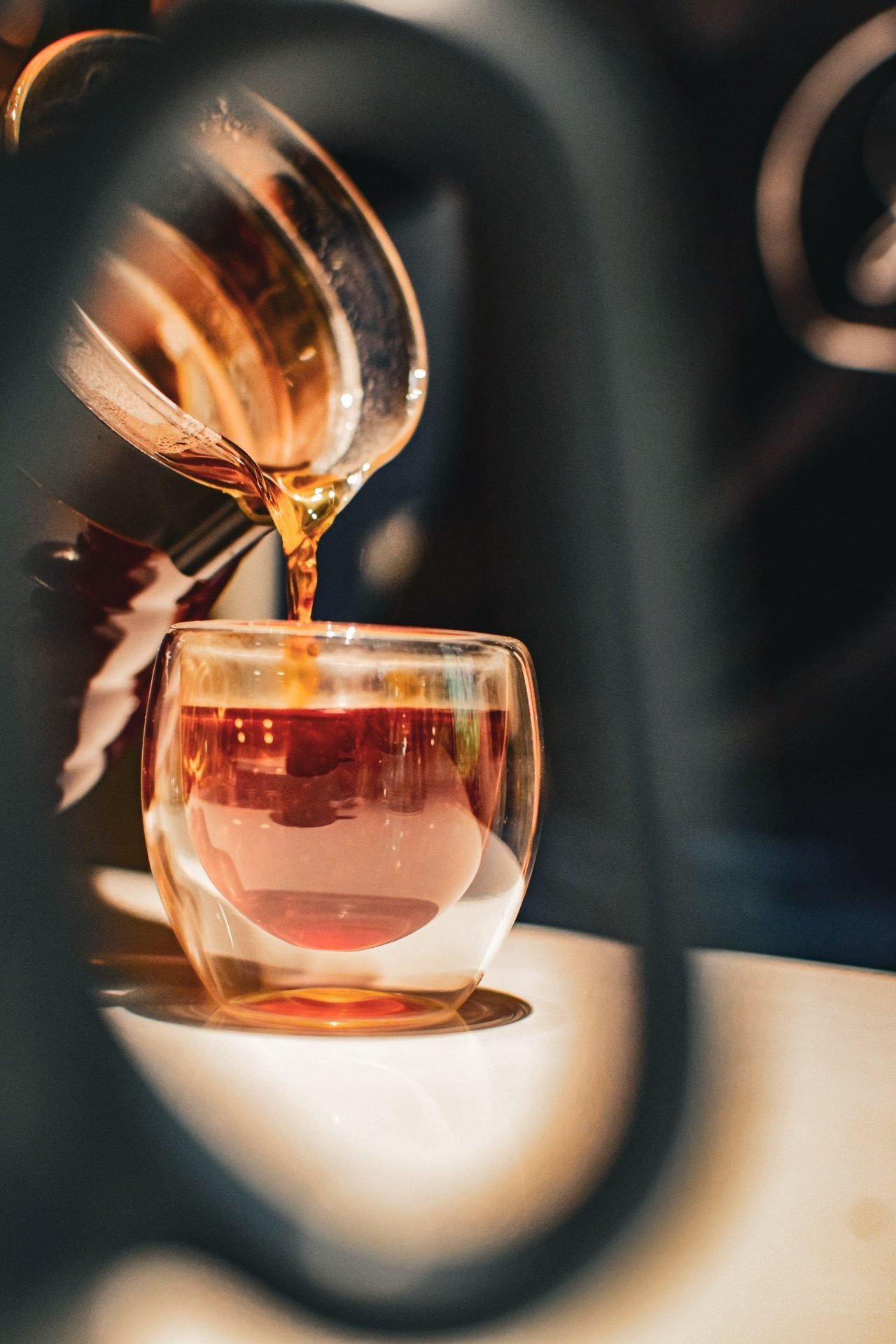 Café recién preparado cayendo en una taza de vidrio